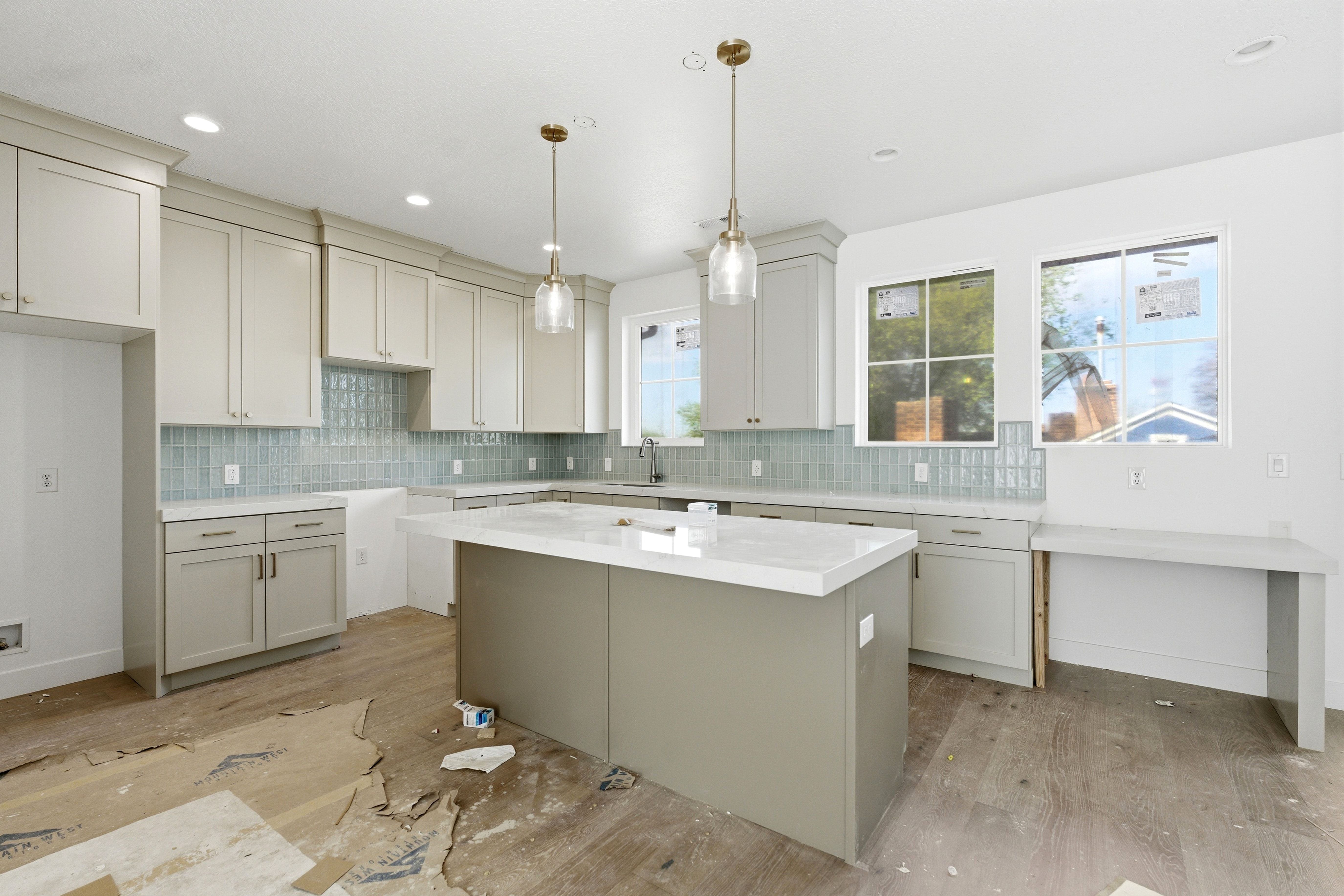 Kitchen featuring backsplash, a kitchen island, wood finished floors, and hanging light fixtures