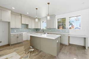 Kitchen featuring backsplash, a kitchen island, wood finished floors, and hanging light fixtures