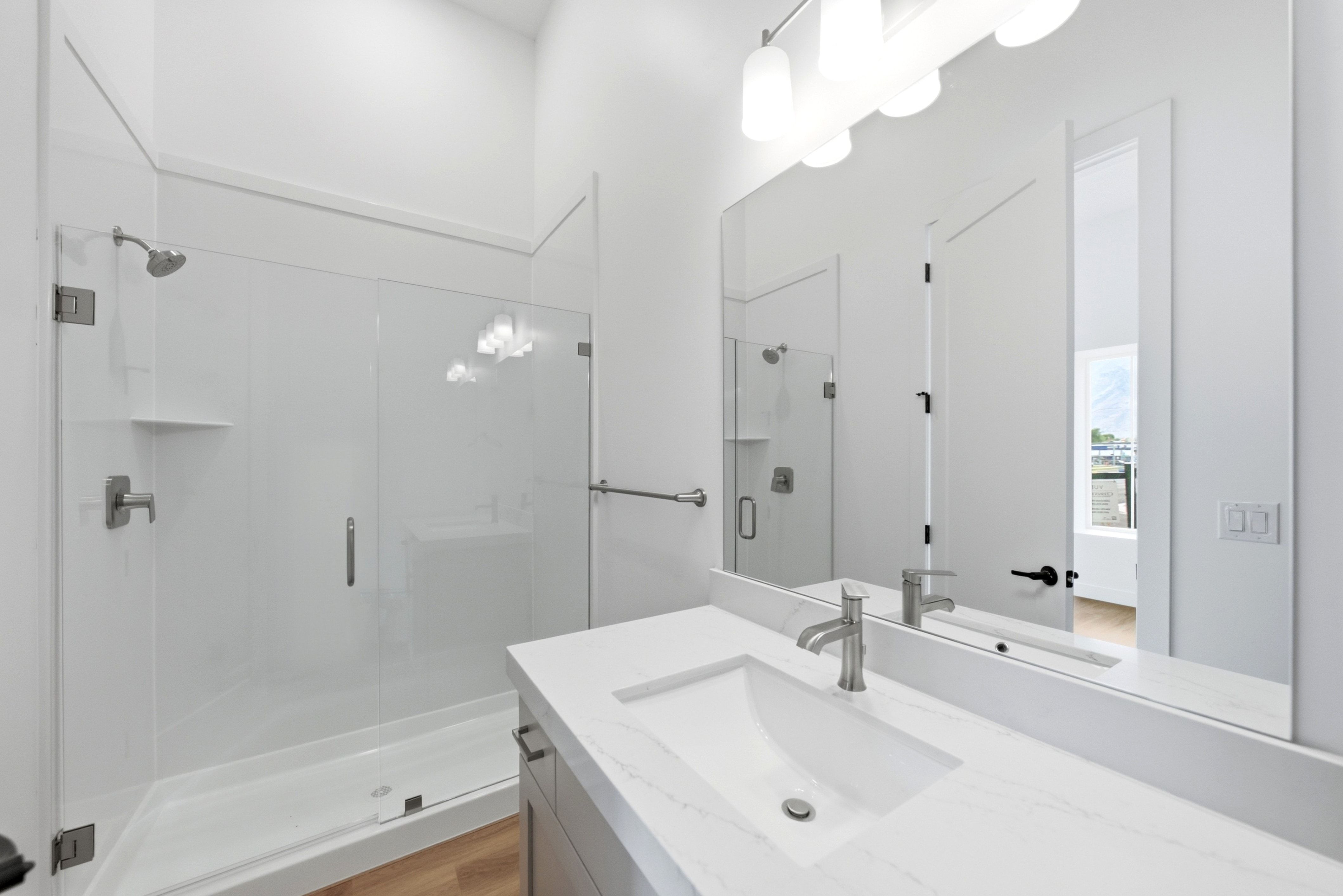 Contemporary bathroom featuring a spacious vanity with an integrated sink, a quartz-finish countertop, and brushed nickel fixtures