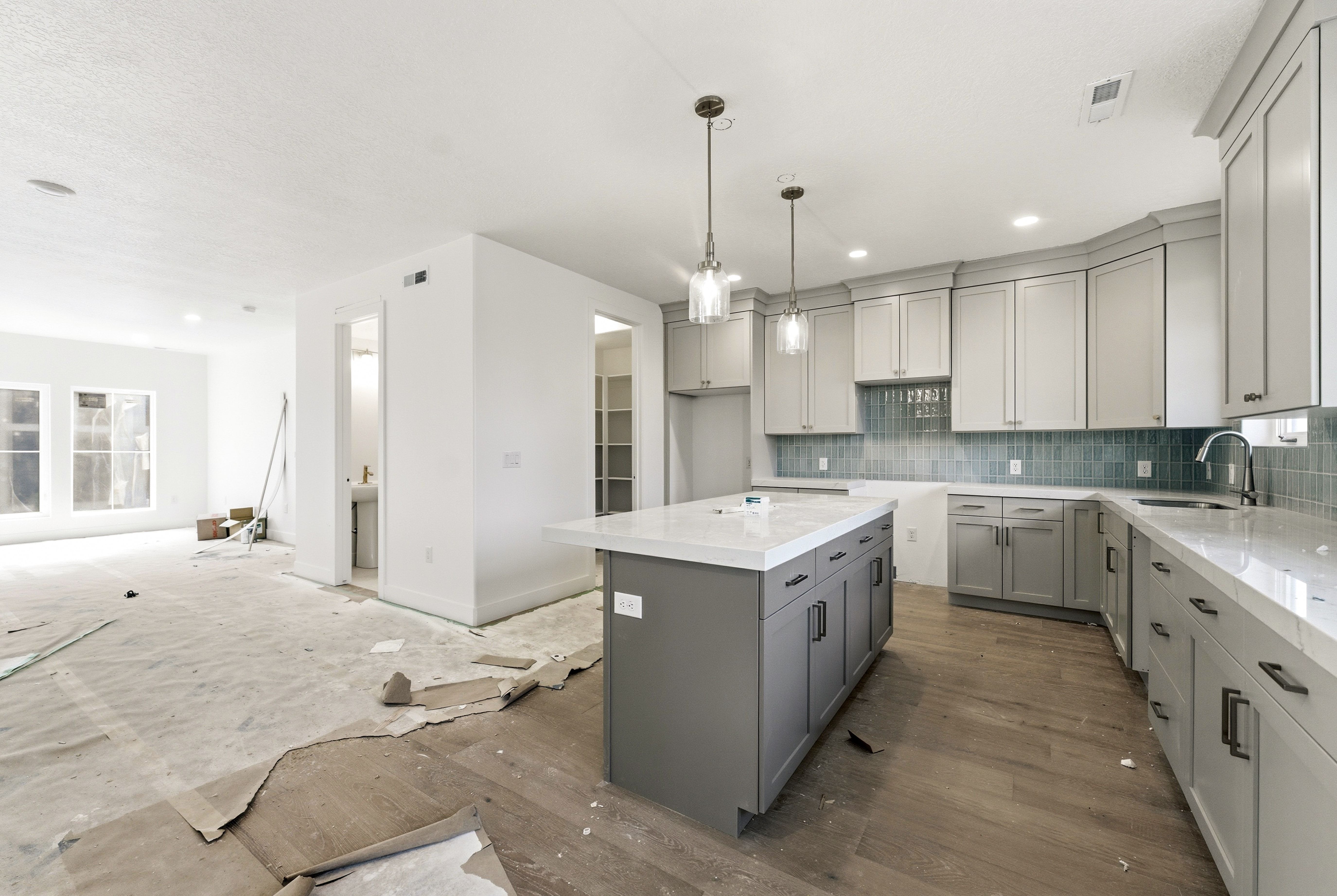 Kitchen with gray cabinetry, a center island, light stone counters, tasteful backsplash, and hanging light fixtures