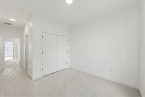 Unfurnished bedroom featuring light colored carpet and a closet