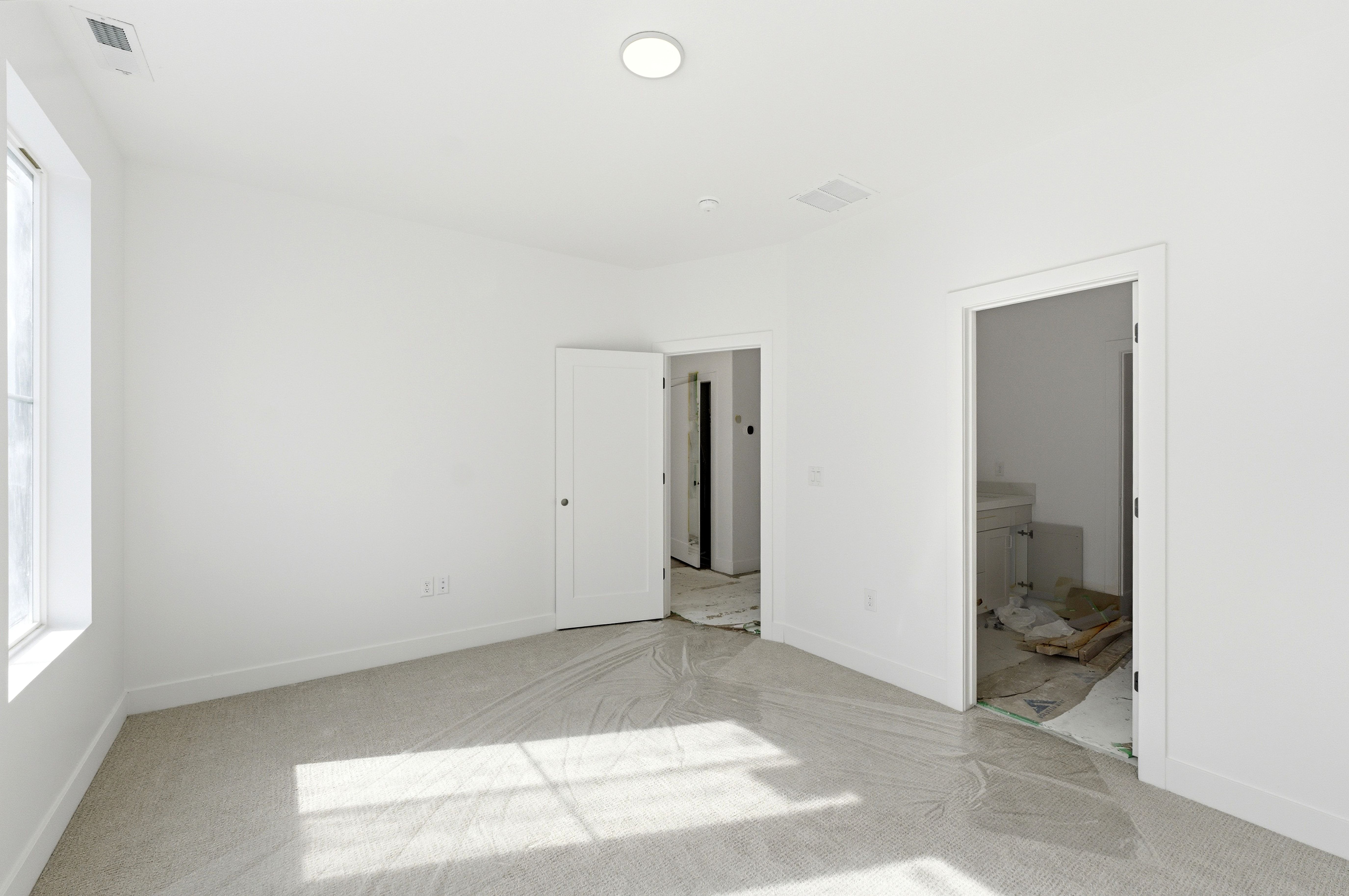 Unfurnished bedroom featuring connected bathroom and light carpet