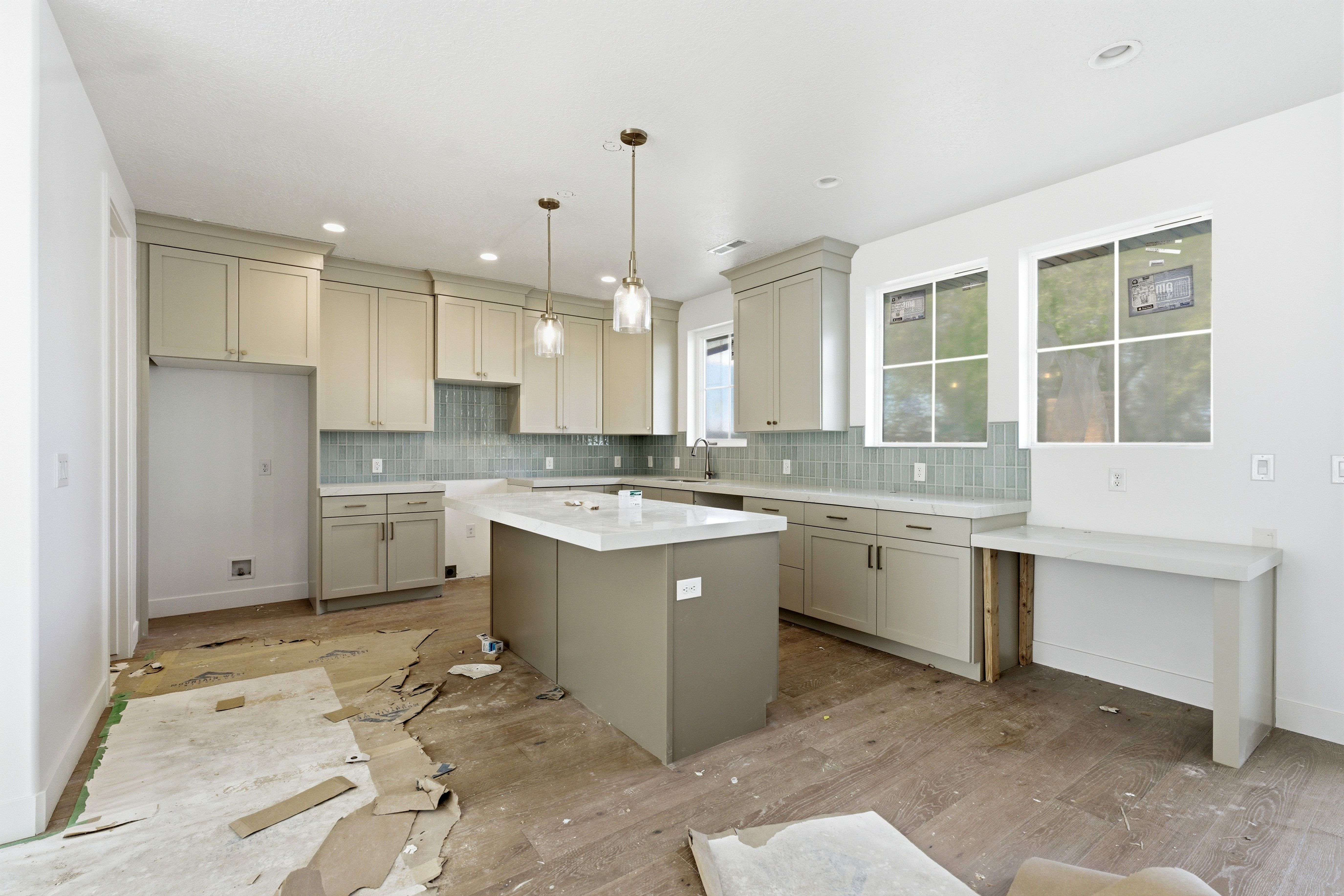 Kitchen with a kitchen island, tasteful backsplash, wood finished floors, and pendant lighting