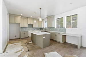 Kitchen with a kitchen island, tasteful backsplash, wood finished floors, and pendant lighting