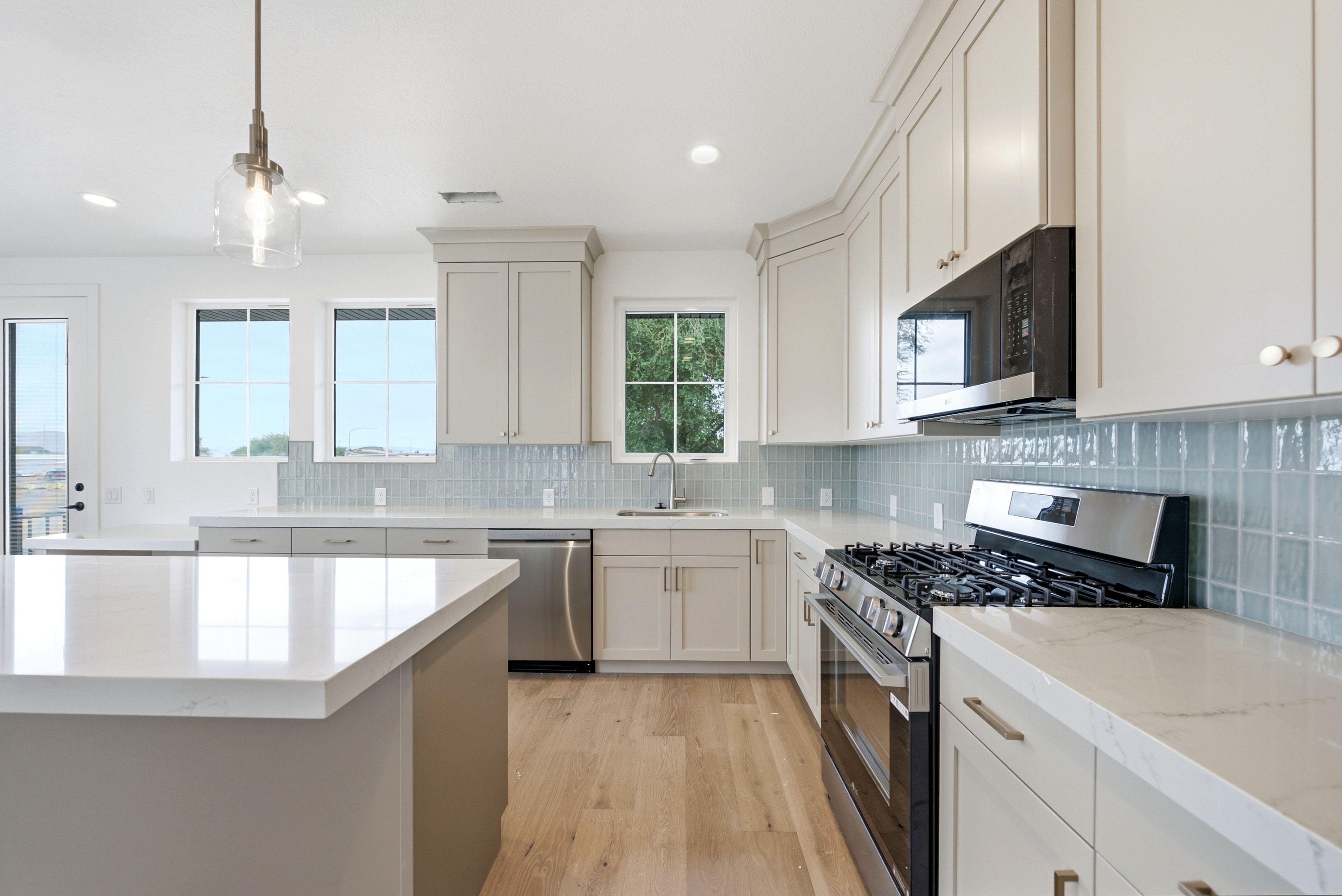 Contemporary kitchen featuring light wood-finish flooring, white countertops, and a full suite of stainless steel appliances