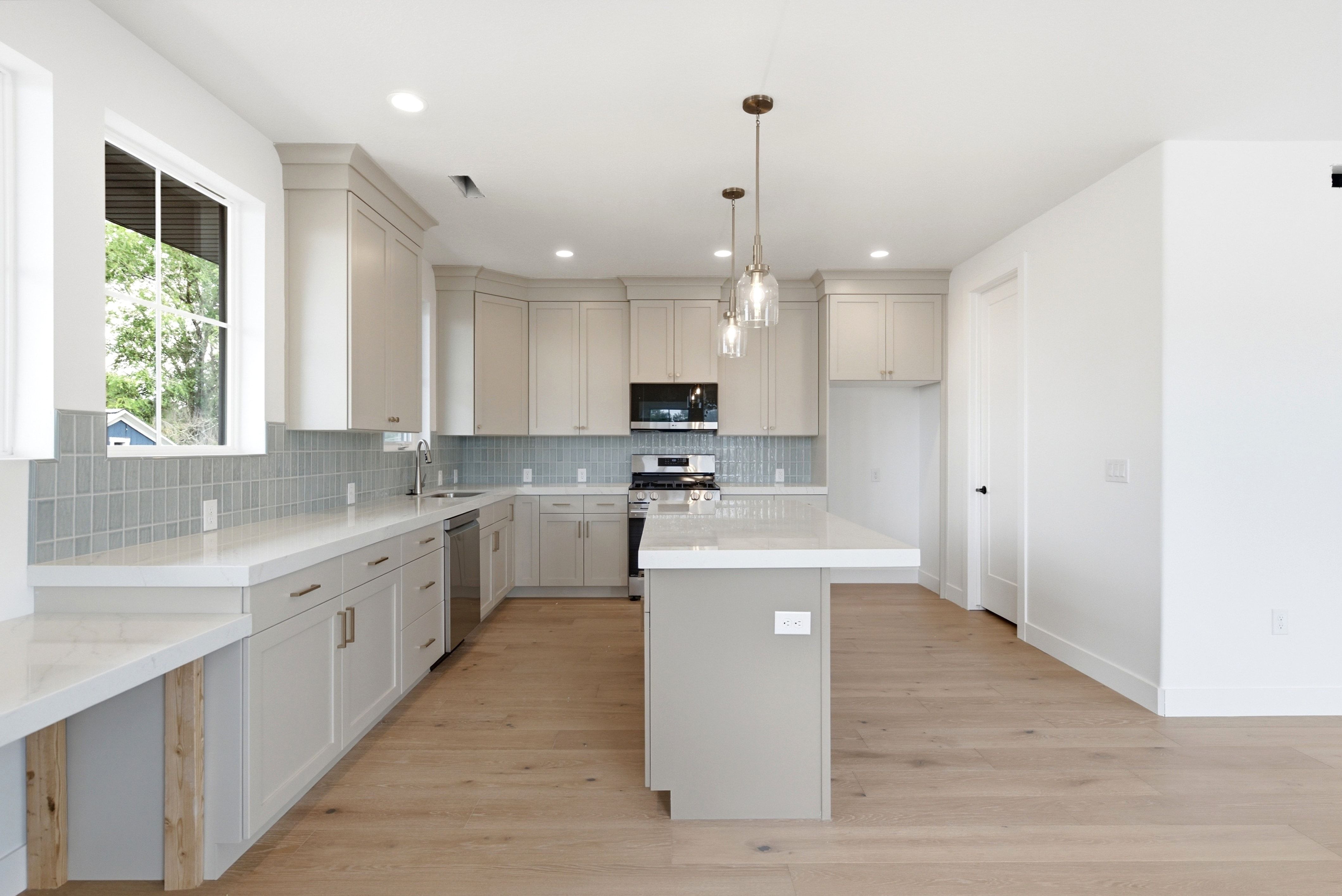 Kitchen featuring light wood-finish flooring, white perimeter cabinetry, light quartz countertops, and a light blue tile backsplash