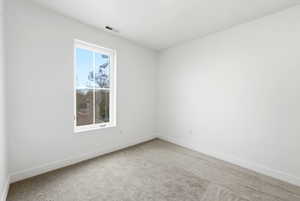 Spare room featuring light carpet and baseboards