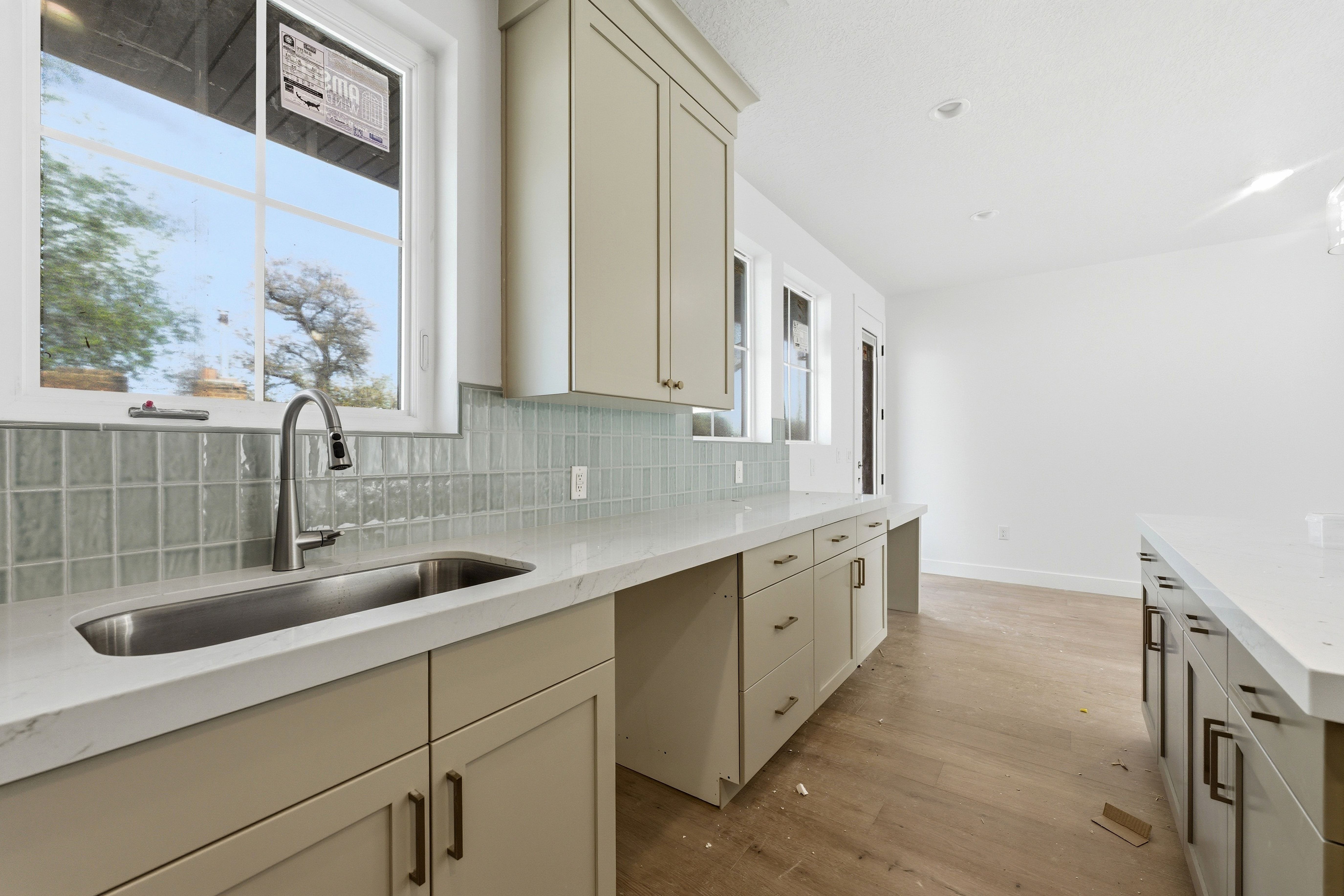 Kitchen featuring light stone countertops, light wood finished floors, cream cabinetry, and tasteful backsplash
