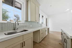 Kitchen featuring light stone countertops, light wood finished floors, cream cabinetry, and tasteful backsplash