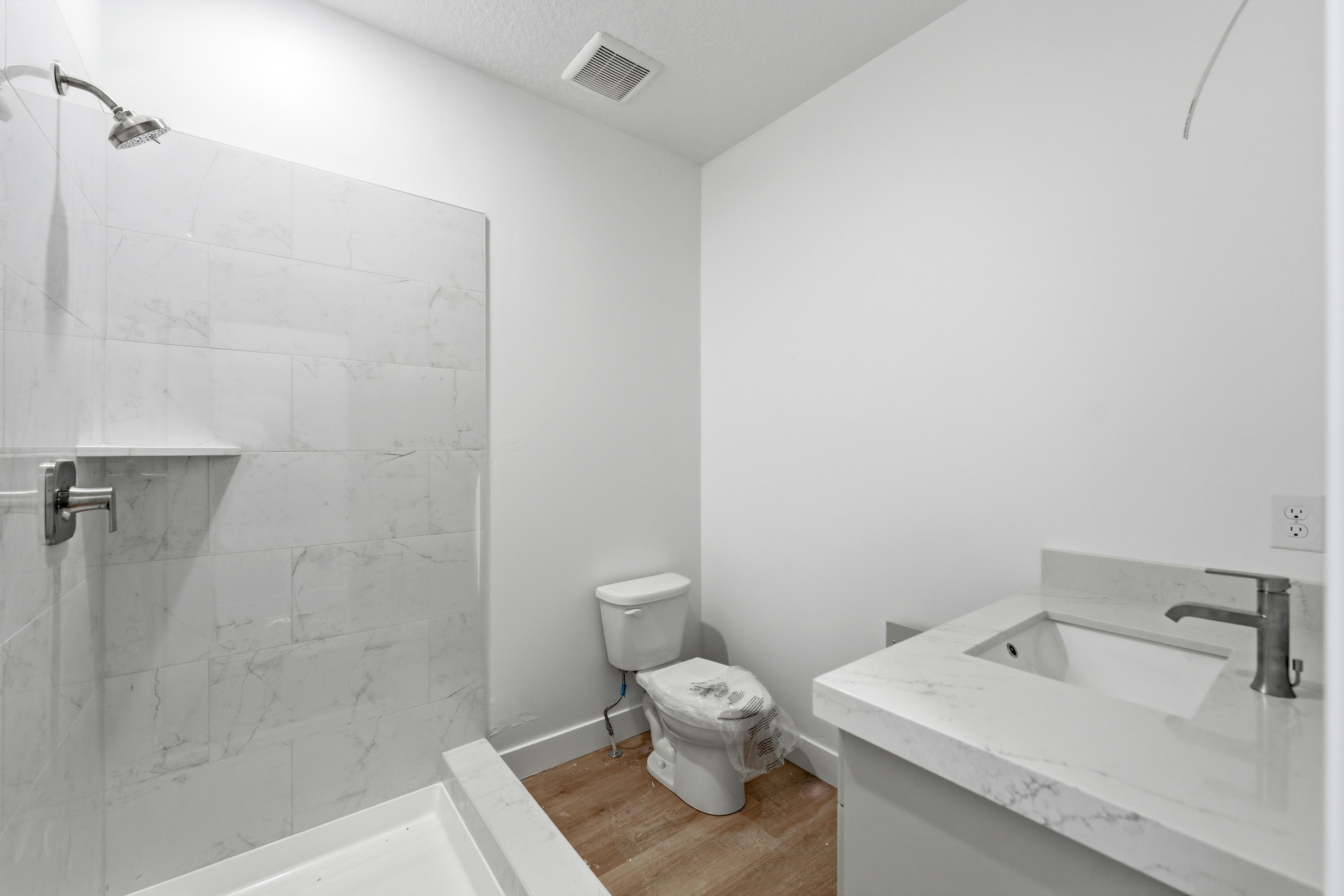 Full bathroom with vanity, a marble finish shower, and light wood finished floors