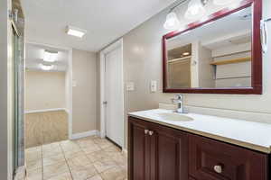 Bathroom featuring a stall shower, vanity, and light tile patterned floors