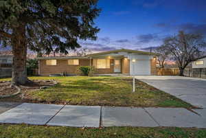 Single story home with brick siding, an attached garage, concrete driveway, and covered porch