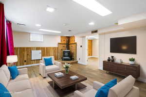 Living area with a wood stove, wooden walls, wainscoting, and wood finished floors