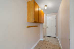 Hall featuring baseboards and light tile patterned flooring
