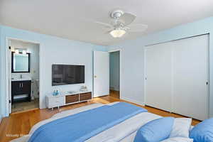 Bedroom featuring wood finished floors, ceiling fan, a closet, and ensuite bath