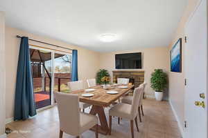 Dining space featuring a lit fireplace and light tile patterned floors