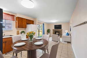 Dining space featuring a stone fireplace and light tile patterned floors