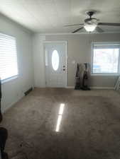 Carpeted entryway featuring a ceiling fan and baseboards