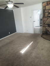Unfurnished living room featuring carpet, ceiling fan, and crown molding