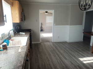 Kitchen featuring gas range oven, dark wood-type flooring, stainless steel microwave, a ceiling fan, and wainscoting