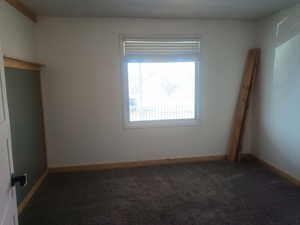 Spare room featuring dark colored carpet and baseboards