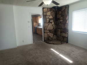 Unfurnished living room featuring ceiling fan, carpet flooring, and crown molding