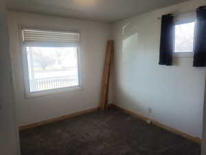 Spare room with dark colored carpet and baseboards