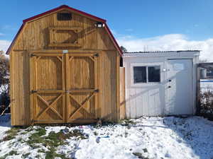 Snow covered structure featuring a shed