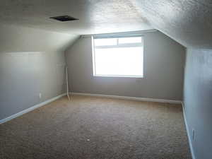 Bonus room featuring a textured ceiling, vaulted ceiling, and carpet floors