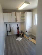 Laundry room featuring dark wood-style flooring, hookup for a washing machine, and cabinet space