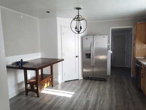 Kitchen featuring appliances with stainless steel finishes, a chandelier, hanging light fixtures, and dark wood-style flooring