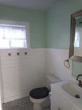 Bathroom featuring vanity, a wainscoted wall, and tile walls