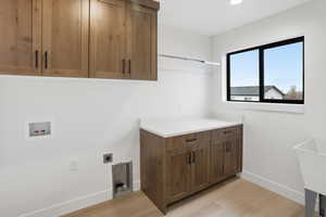Laundry area with light wood-style floors, cabinet space, washer hookup, hookup for an electric dryer, and recessed lighting