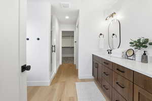 Full bath featuring double vanity, a walk in closet, light wood-style flooring, and recessed lighting