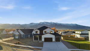 View of front of property featuring a residential view, driveway, stucco siding, and a mountain view