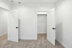 Unfurnished bedroom featuring light carpet and a spacious closet