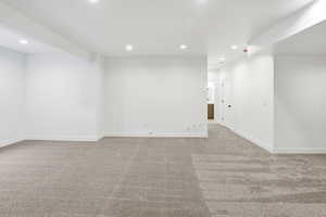 Empty room with light carpet and recessed lighting