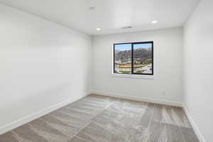 Empty room with light carpet, recessed lighting, and a mountain view