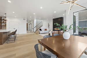 Dining space featuring a large fireplace, light wood-style floors, recessed lighting, and stairs