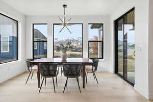 Dining area featuring a mountain view, a chandelier, plenty of natural light, and light wood-style floors