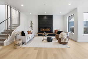 Living area featuring stairs, light wood-style flooring, recessed lighting, and a fireplace
