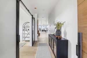 Corridor featuring a barn door and light wood finished floors