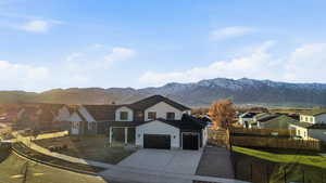 View of front of home featuring a residential view, stucco siding, a mountain view, and driveway