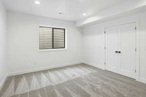 Unfurnished bedroom with light colored carpet, recessed lighting, and a closet