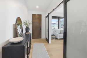 Hallway featuring light wood-style flooring and a barn door