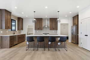 Kitchen featuring decorative light fixtures, a kitchen island, a breakfast bar area, light wood-style flooring, and recessed lighting