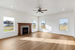 Unfurnished living room with a tiled fireplace, light wood-style flooring, healthy amount of natural light, and recessed lighting