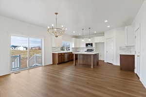 Kitchen with a center island, decorative light fixtures, a kitchen bar, a chandelier, and white cabinetry