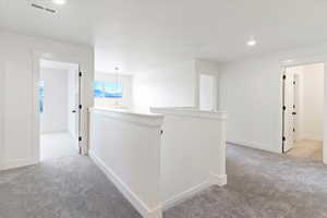Hall featuring an upstairs landing, recessed lighting, and light colored carpet