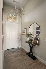 Foyer entrance with dark wood-style flooring and a chandelier